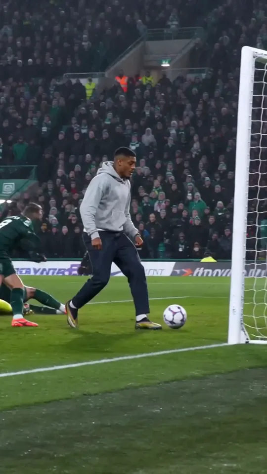 Ozil goal AI video frame: a defender slides past on the wet grass while he holds the ball by the goal